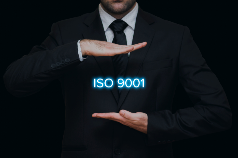 ISO 9001 felirat egy öltönyös ember kezei között